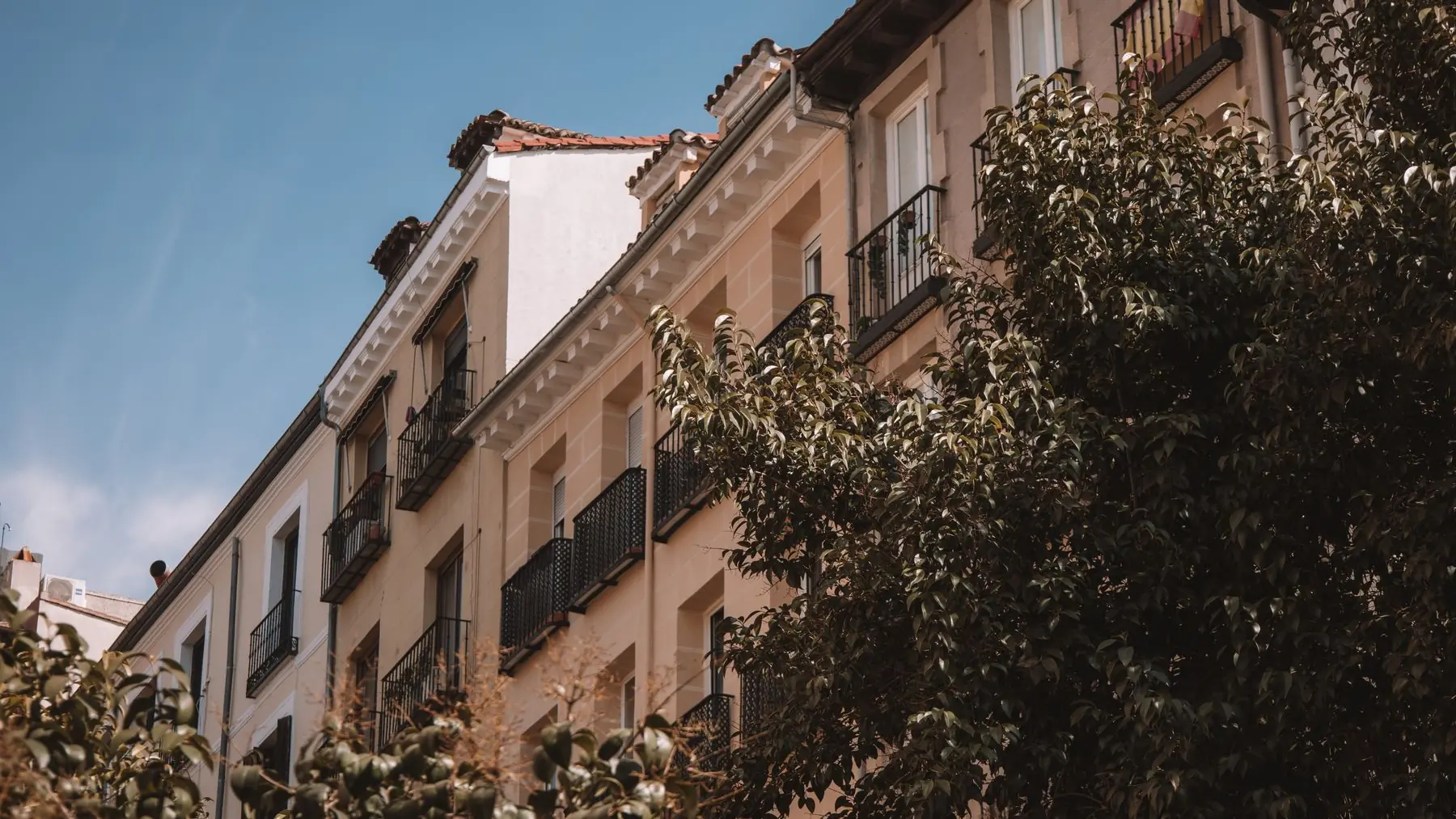 Fachada de un bloque de viviendas con balcones en una calle residencial