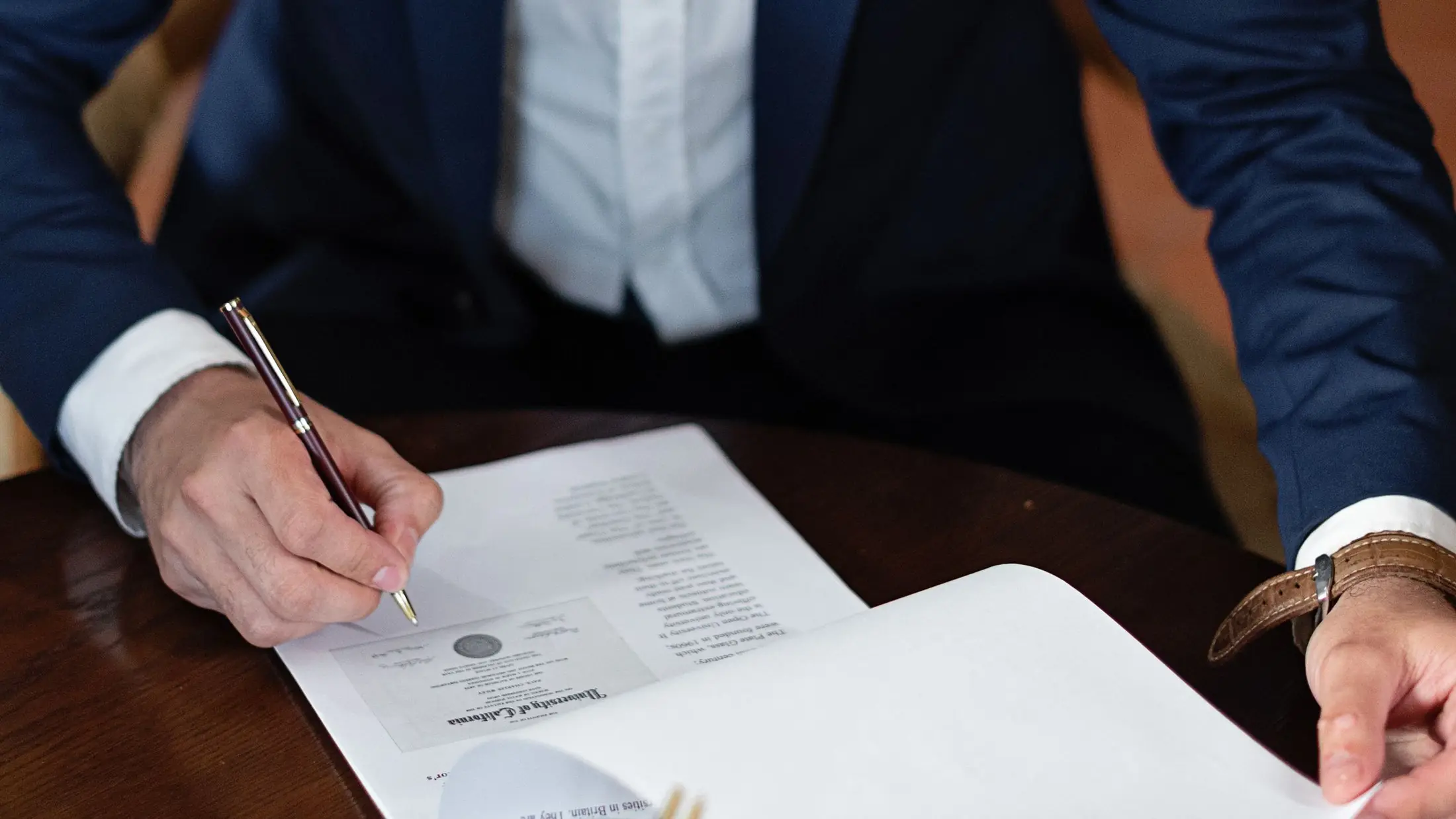 Persona firmando un documento en la mesa de un despacho