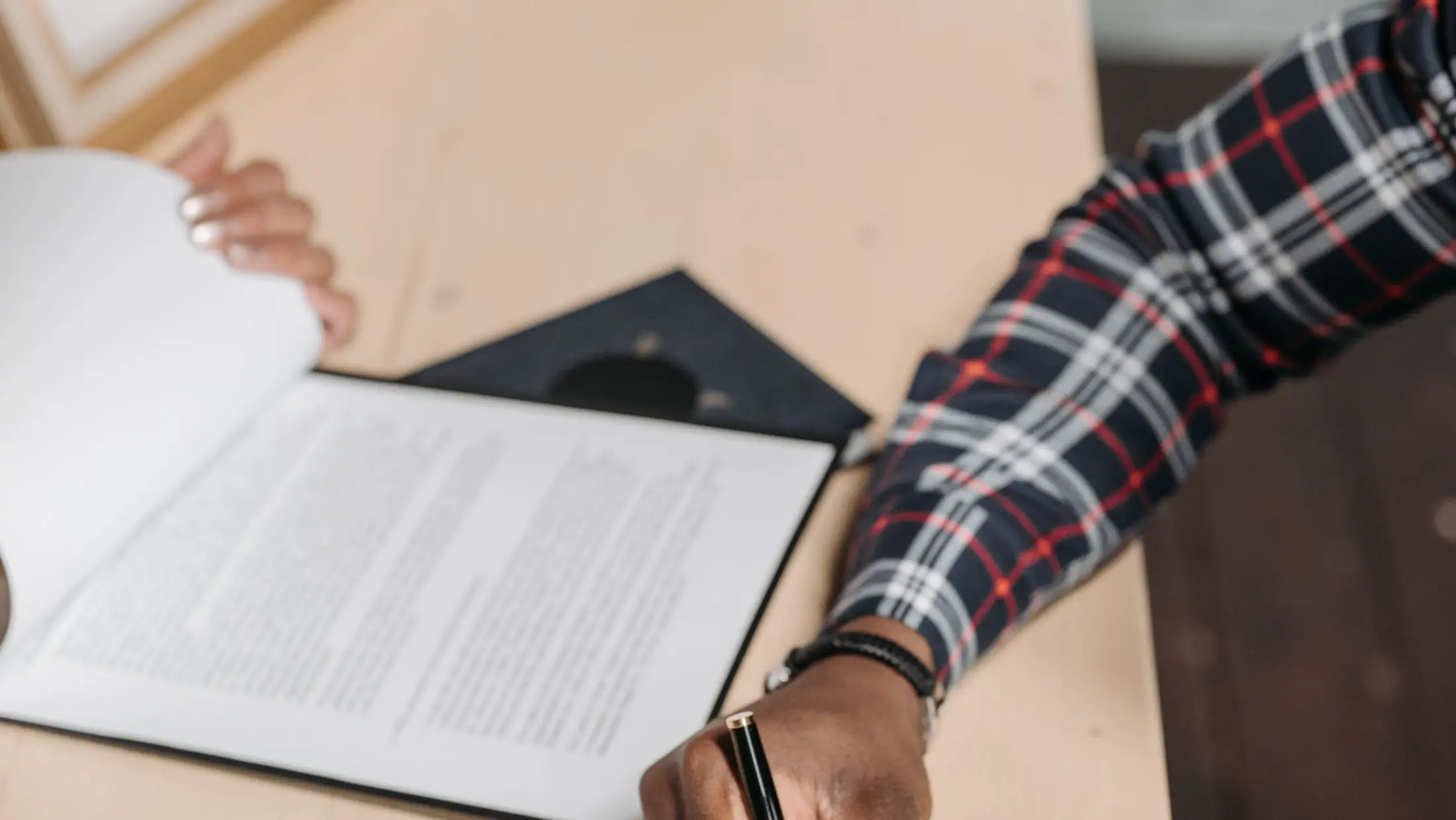 Manos revisando y firmando documentación oficial sobre la mesa